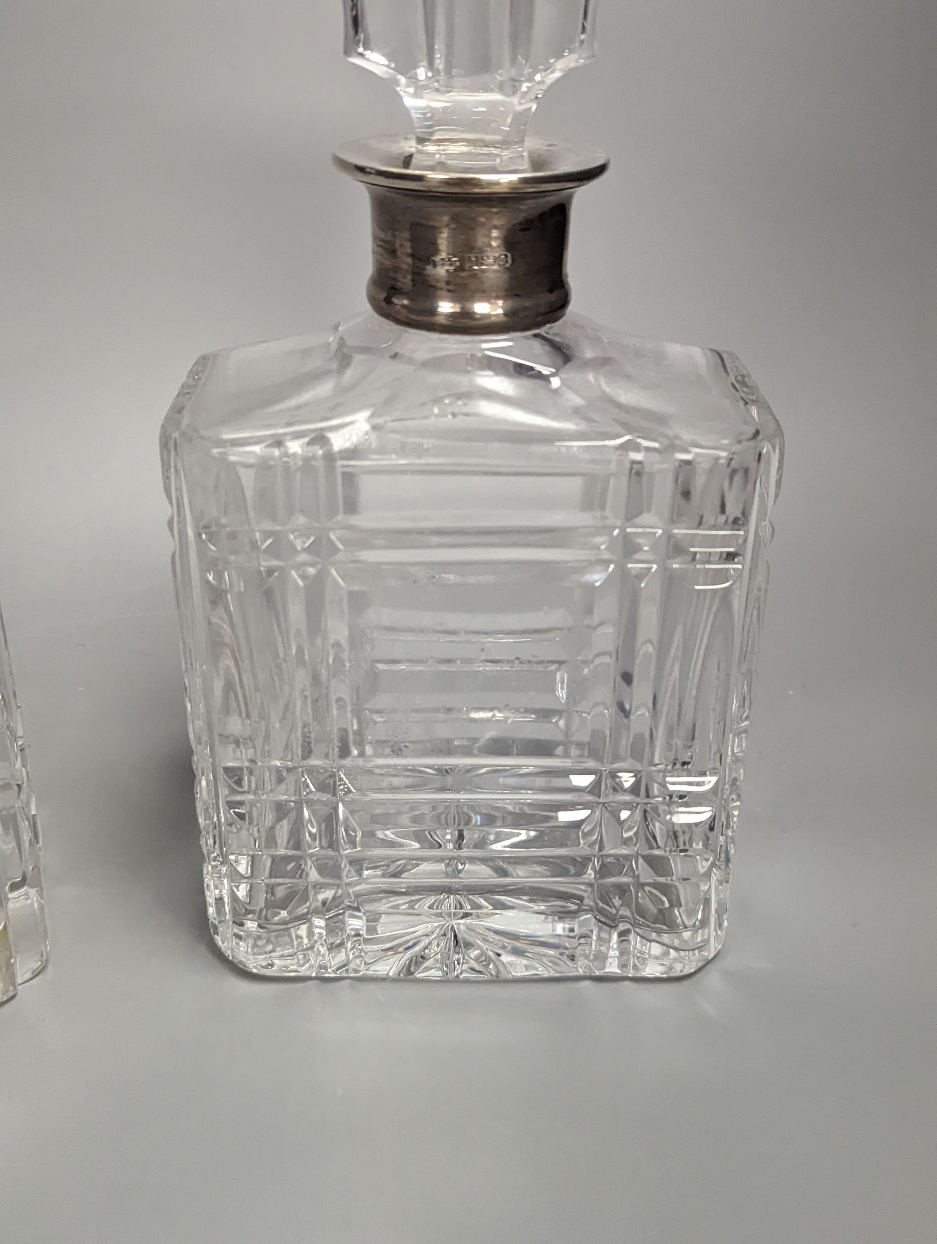 A pair of silver mounted cut glass decanters, with mis-matched stoppers